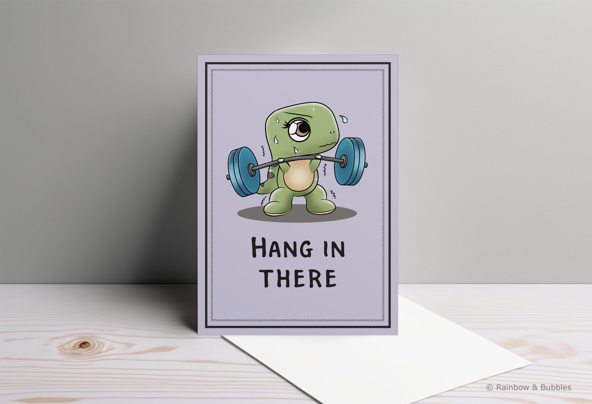 A kawaii greeting card from Rainbow & Bubbles, showing a t-rex struggling to lift weights with his tiny arms.