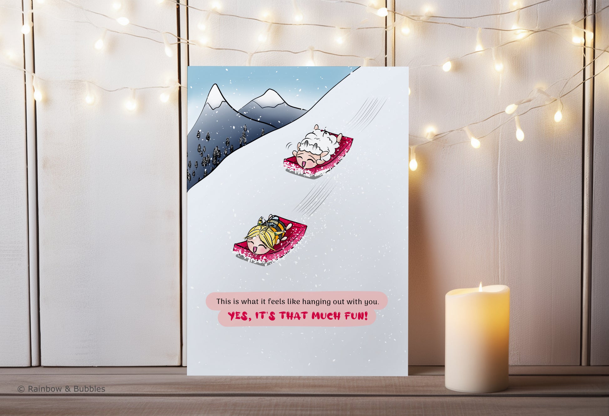 A kawaii greeting card from Rainbow & Bubbles, showing a sheep and a bee having fun snow sledding.