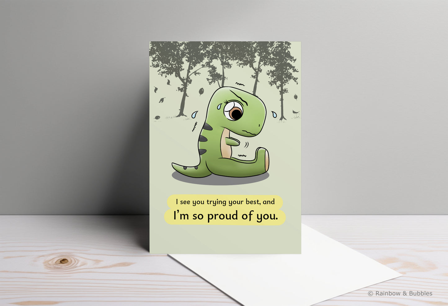 A kawaii greeting card from Rainbow & Bubbles, showing a t-rex stretching and struggling to touch his toes with his little arms.